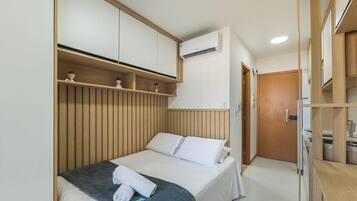 Una habitación de hotel con cama, armario, baño y aire acondicionado.