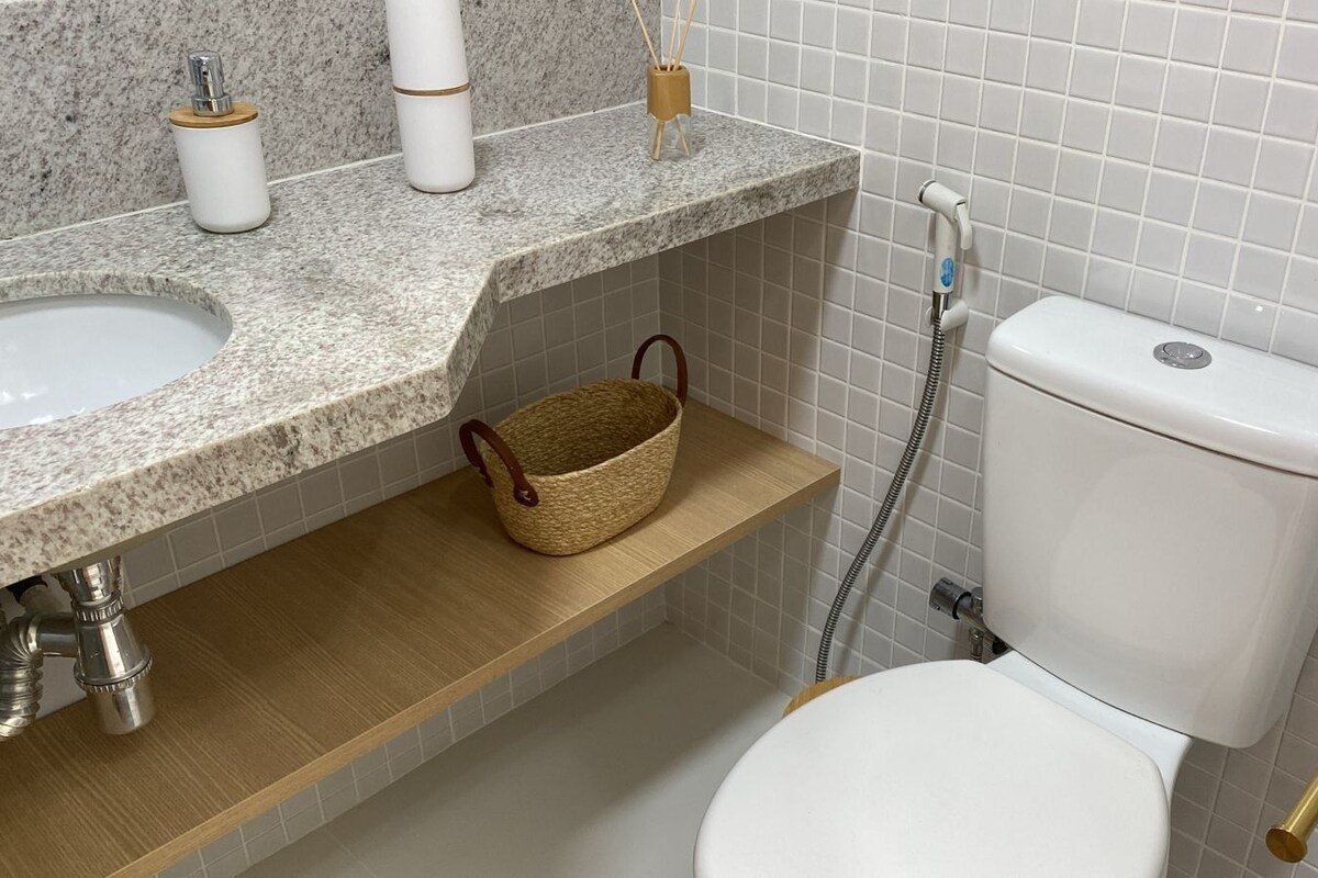 Ein Badezimmer mit Toilette, Waschbecken, Dusche und einem Regal mit Korb.