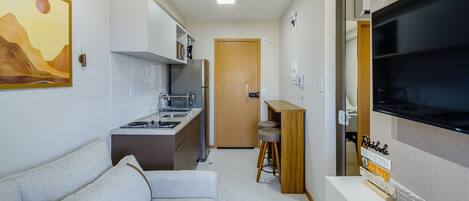 A compact living space with a kitchenette, a sofa, a TV, and a small dining area.