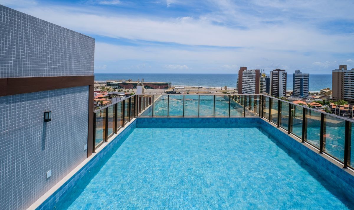 A rooftop pool with a view of the ocean and cityscape.
