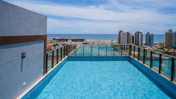 A rooftop pool with a view of the ocean and cityscape.