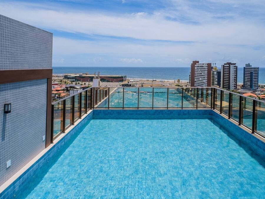 A rooftop pool with a view of the ocean and surrounding buildings.