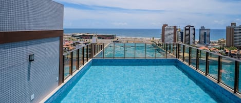A rooftop pool with a view of the ocean and surrounding buildings.