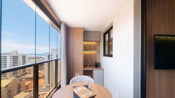 A balcony with a city view, a small table with glasses, and a TV on the wall.