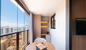 Ein Balkon mit Blick auf die Stadt, ein kleiner Tisch mit Gläsern und ein Fernseher an der Wand.