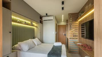 Une chambre d’hôtel moderne équipée d’un lit, d’une télévision, d’une armoire intégrée et d’une étagère murale agrémentée d’objets décoratifs.