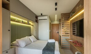 A modern hotel room with a bed, a TV, a built-in wardrobe, and a wall-mounted shelf with decorative items. - SMT - Building 750m From the Beach in Salvador (Salvador)