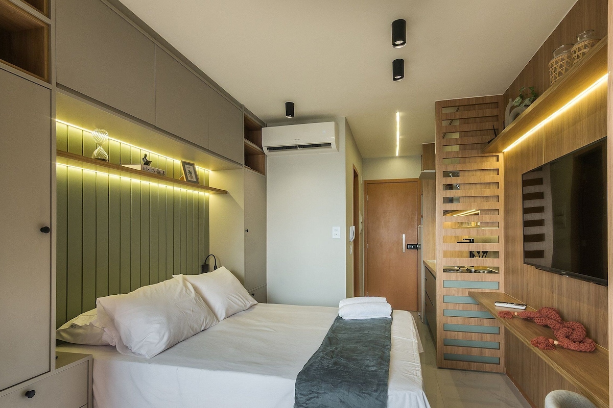 Une chambre d’hôtel moderne équipée d’un lit, d’une télévision, d’une armoire intégrée et d’une étagère murale agrémentée d’objets décoratifs.