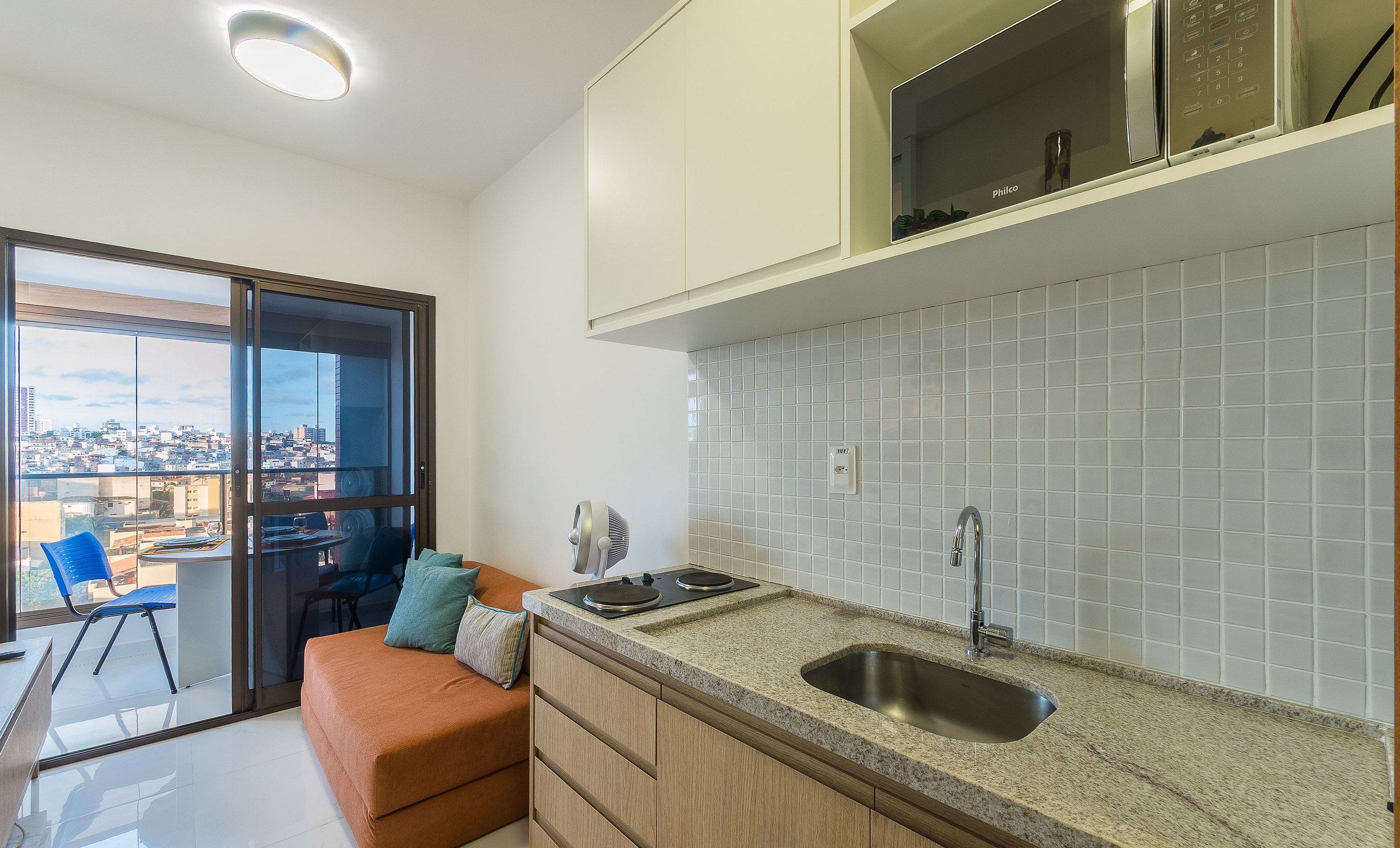 A modern kitchen with a built-in oven, a sink, and a window overlooking a cityscape.