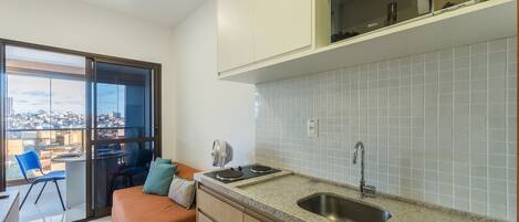 A modern kitchen with a built-in oven, a sink, and a window overlooking a cityscape.