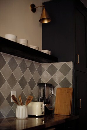 A kitchen with a modern design, featuring a microwave, toaster, and a cutting board on the counter.