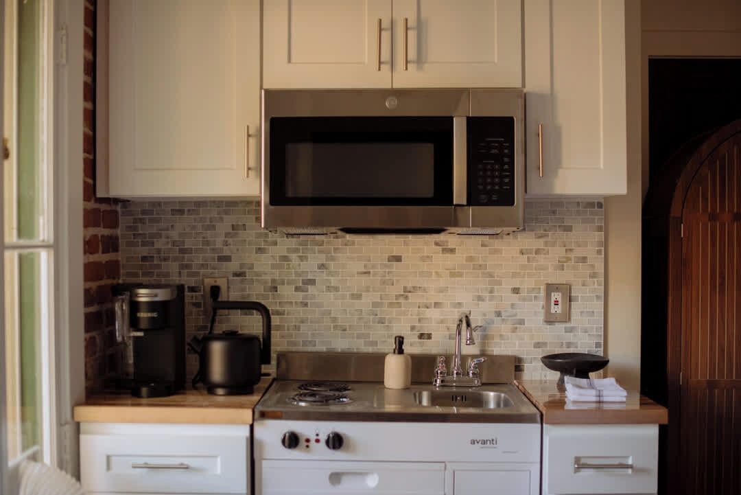Una cocina con microondas, estufa y cafetera.