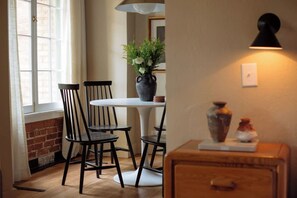 A dining area with a white table, black chairs, a vase with flowers, and a wall-mounted lamp.