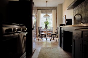 A kitchen with a central island, a dining table with chairs, a hanging light fixture, and a window with curtains. - Elegant Studio in Hollywood (Los Angeles)