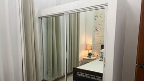 Un dormitorio con puerta corredera para el armario, una mesita de noche con lámpara y una cama con cabecero de madera.