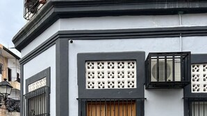 Un edificio con puerta de madera, reja de metal negro y panel decorativo blanco.