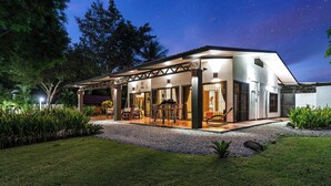 Een modern huis met een overdekte patio, een eethoek en een garage.