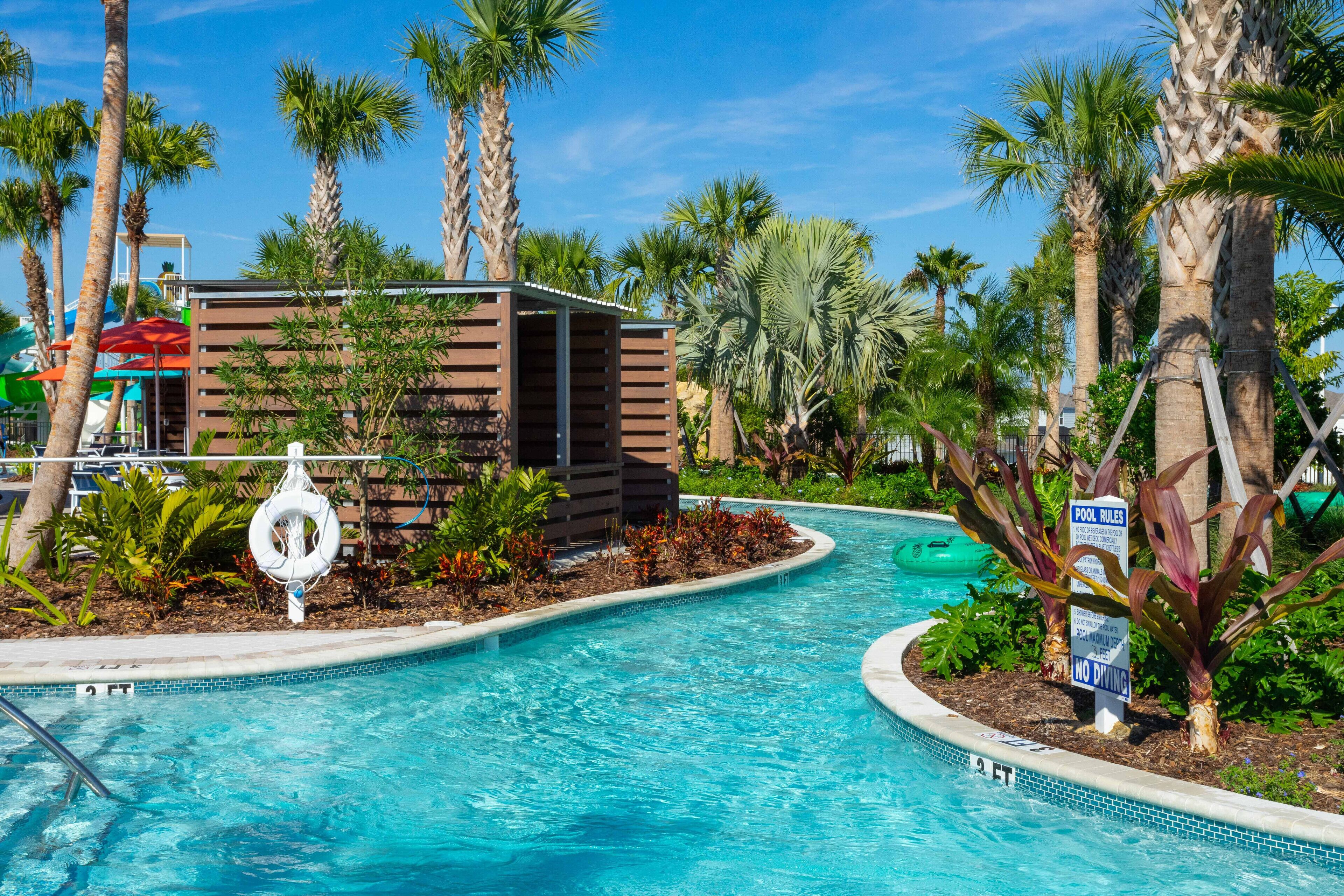 A swimming pool with a wooden structure, palm trees, and a lifeguard stand.