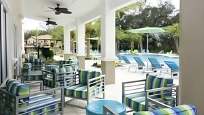 A covered outdoor seating area with lounge chairs and a pool in the background. - Last Minute Disney! Private Pool, Hot Tub, Game Room & Themed Bedrooms. Book Now! #113319 (Orlando)