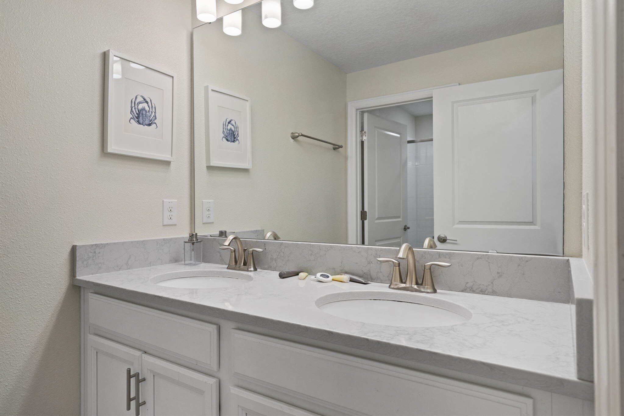 A bathroom with two sinks, a large mirror, and framed artwork on the wall.