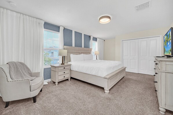 A bedroom with a bed, nightstands, a chair, a dresser, and a TV.