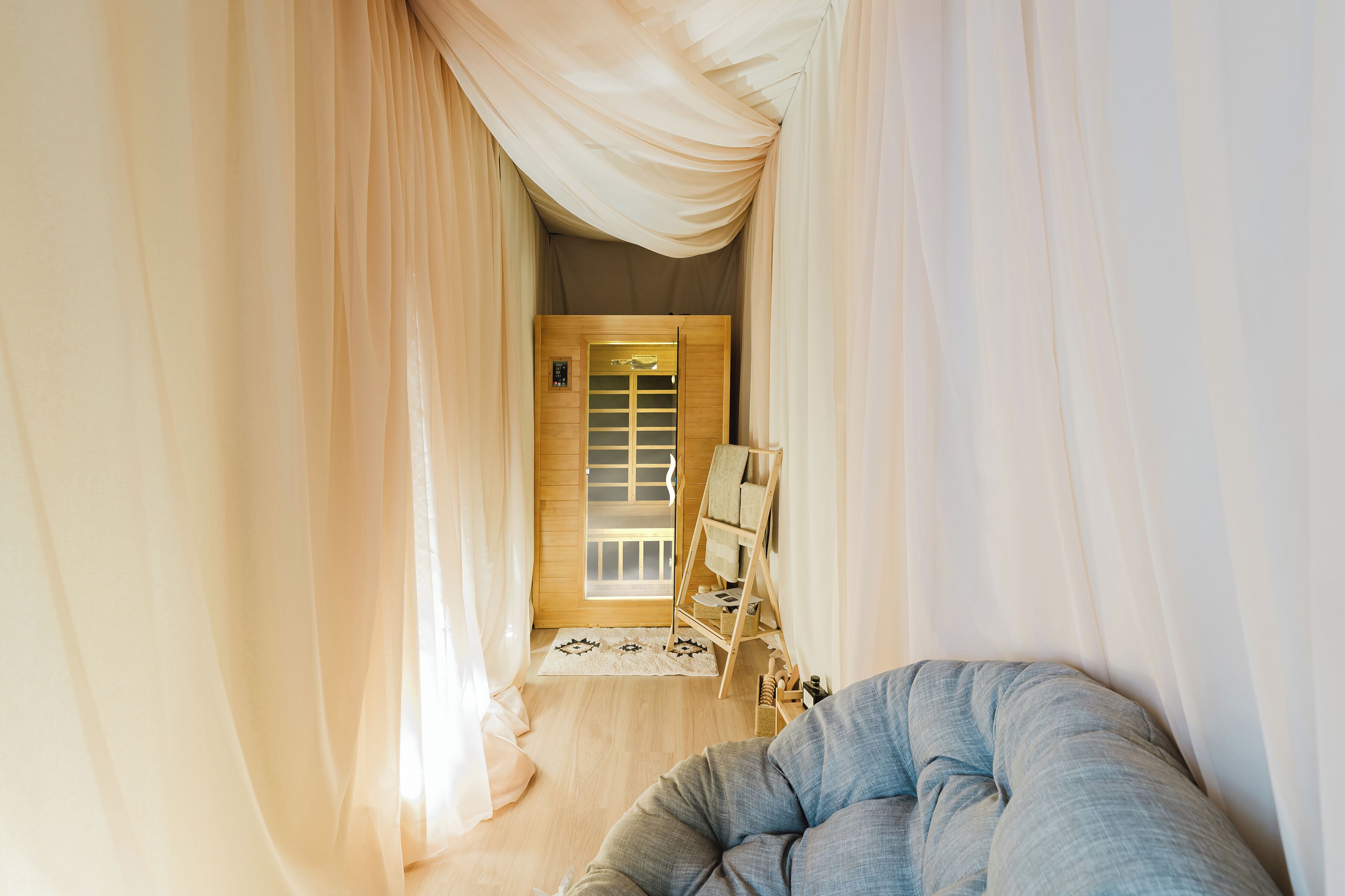 A room with a large window, a wooden door, a bed, and a small table.