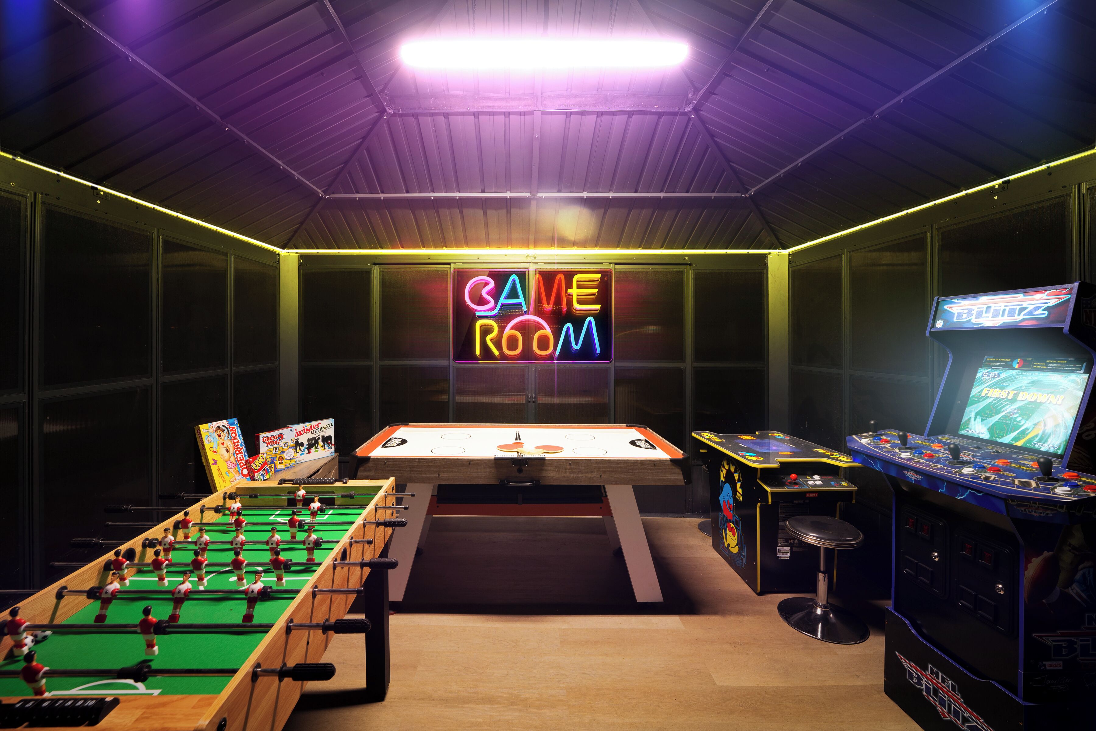 Une salle de jeux équipée d’un baby-foot, d’une table de billard et de jeux d’arcade.