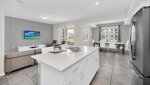 A modern kitchen with a central island, white cabinetry, and a stainless steel refrigerator.