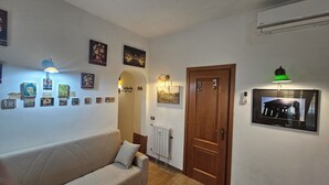 A living room with a sofa, a wooden door, and various framed pictures on the walls. - Cavour 1&2 (Rome)