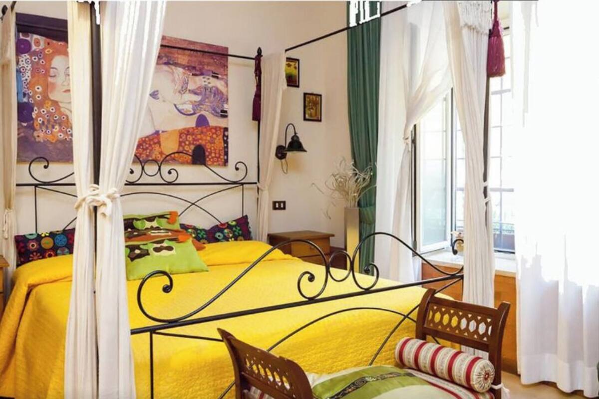 A four-poster bed with a yellow bedspread, a wooden headboard, and a canopy.