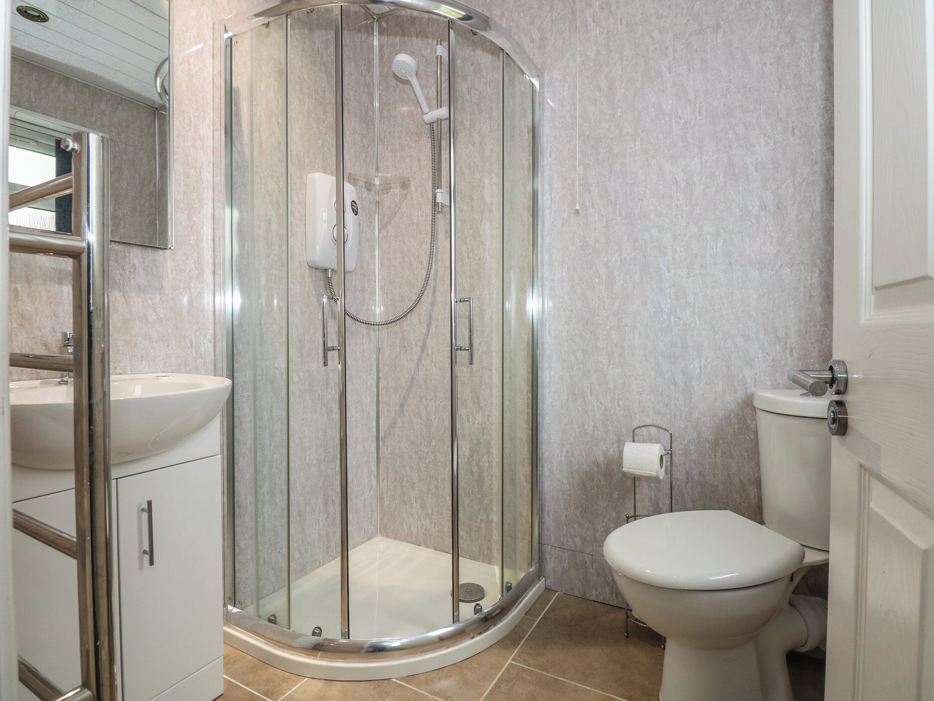 Un baño moderno con ducha de vidrio, un lavamanos blanco y un inodoro.