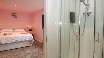 A bedroom with a bed, a nightstand, and a glass-enclosed shower.