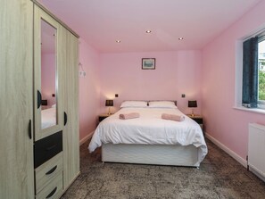 Een slaapkamer met een bed, nachtlampjes, een kledingkast en een raam.