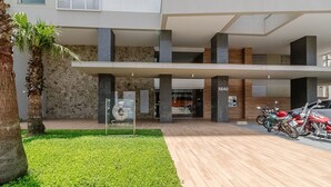 A modern building with a covered entrance, a sign for a summer club, and several parked motorcycles. - Seafront Condominium With Pool - SHC (Picarras)