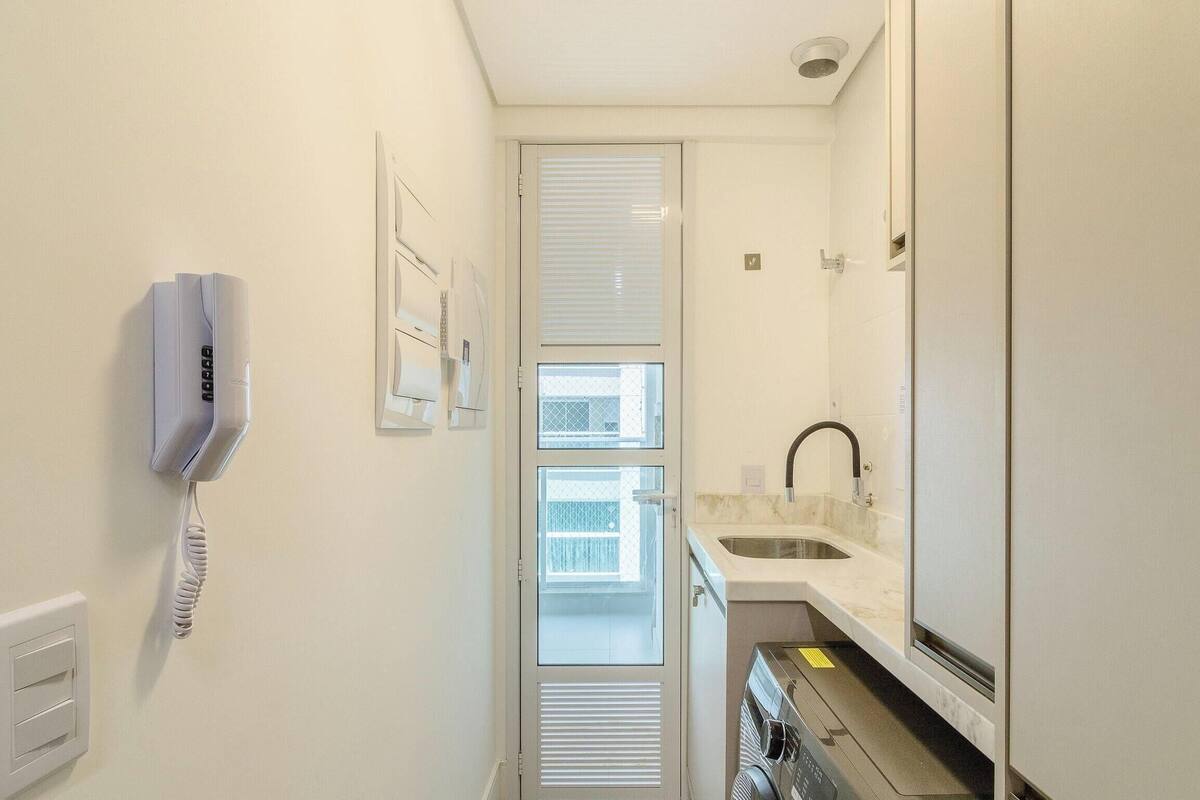 A narrow hallway with a phone, a window, and a sink.