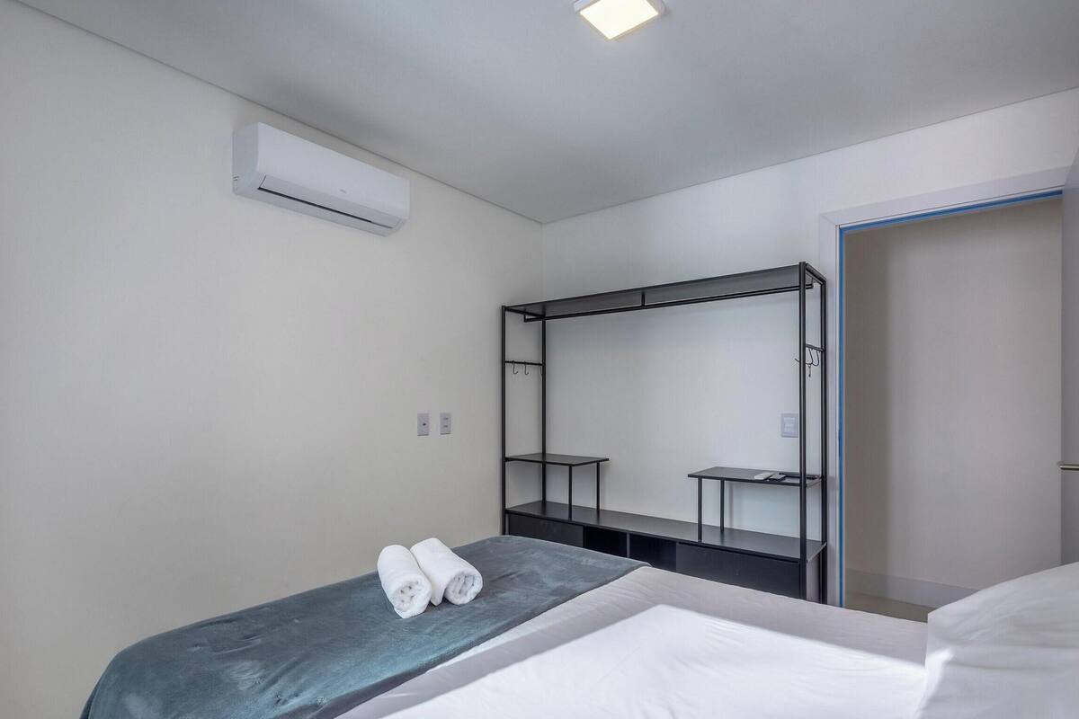A hotel room with a bed, a built-in wardrobe, an air conditioning unit, and a door.