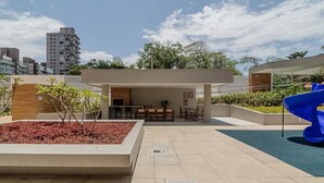 A rooftop patio with outdoor seating, a small garden area, and a blue slide. - Seafront Condominium With Pool - SHC (Picarras)