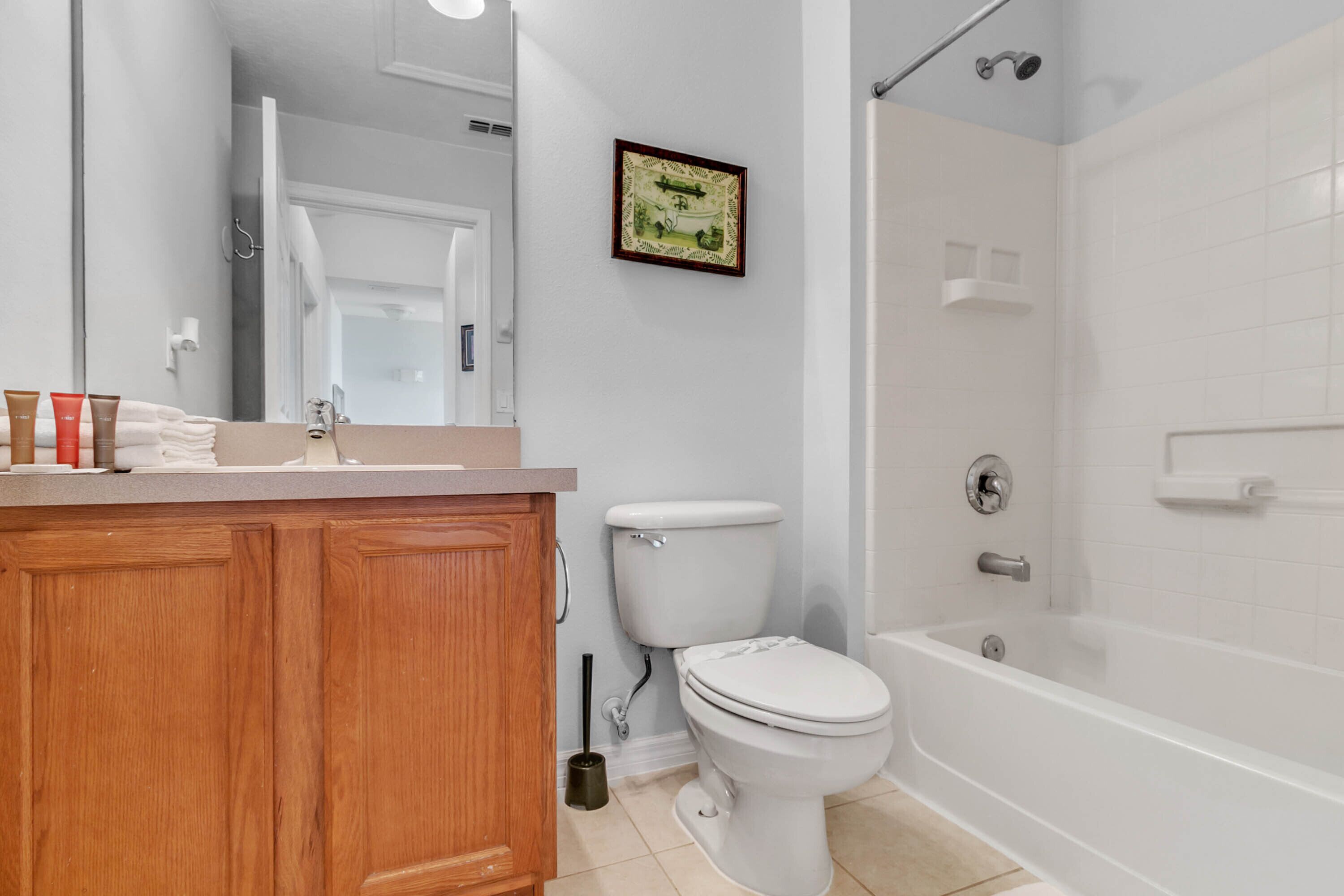 A bathroom with a wooden vanity, a toilet, a bathtub, and a shower.