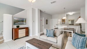 A spacious living room with a sofa, coffee table, and a dining area with a table and chairs.
