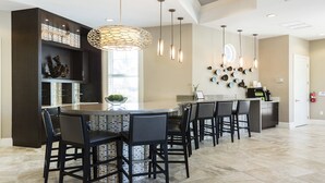 A modern kitchen with a central island, bar stools, pendant lighting, and a decorative wall piece. - Last Minute Disney Getaway! Villa with Private Pool & Hot Tub. Book Now! #116909 (Orlando)