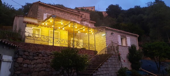 Ein Steinhaus mit Balkon und einer Treppe, die zu dem oberen Stockwerk führt.
