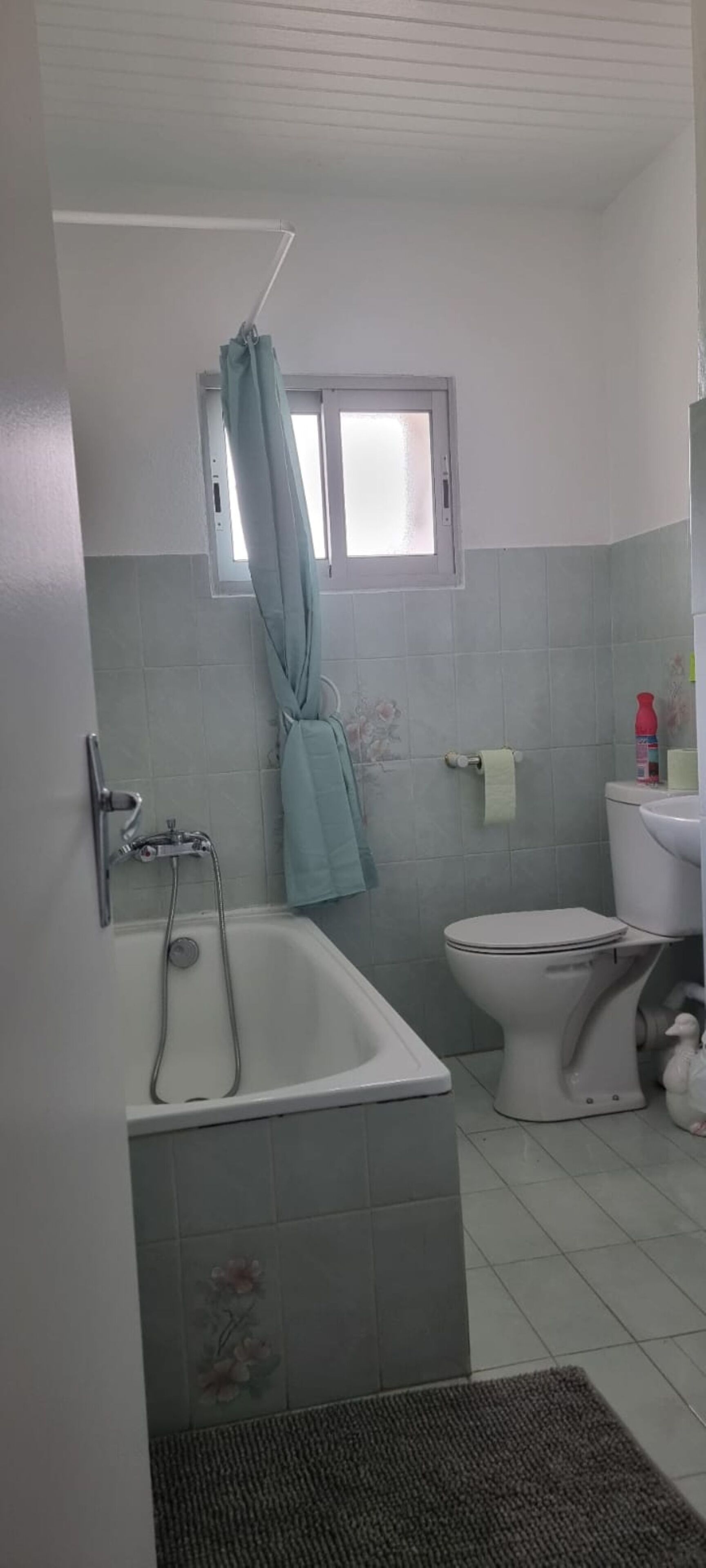 A bathroom with a bathtub, toilet, and a window.