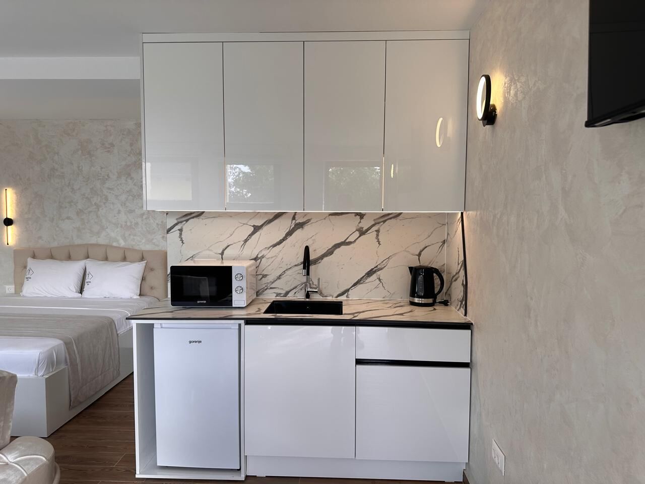 A compact kitchen with a microwave, coffee maker, and a sink.
