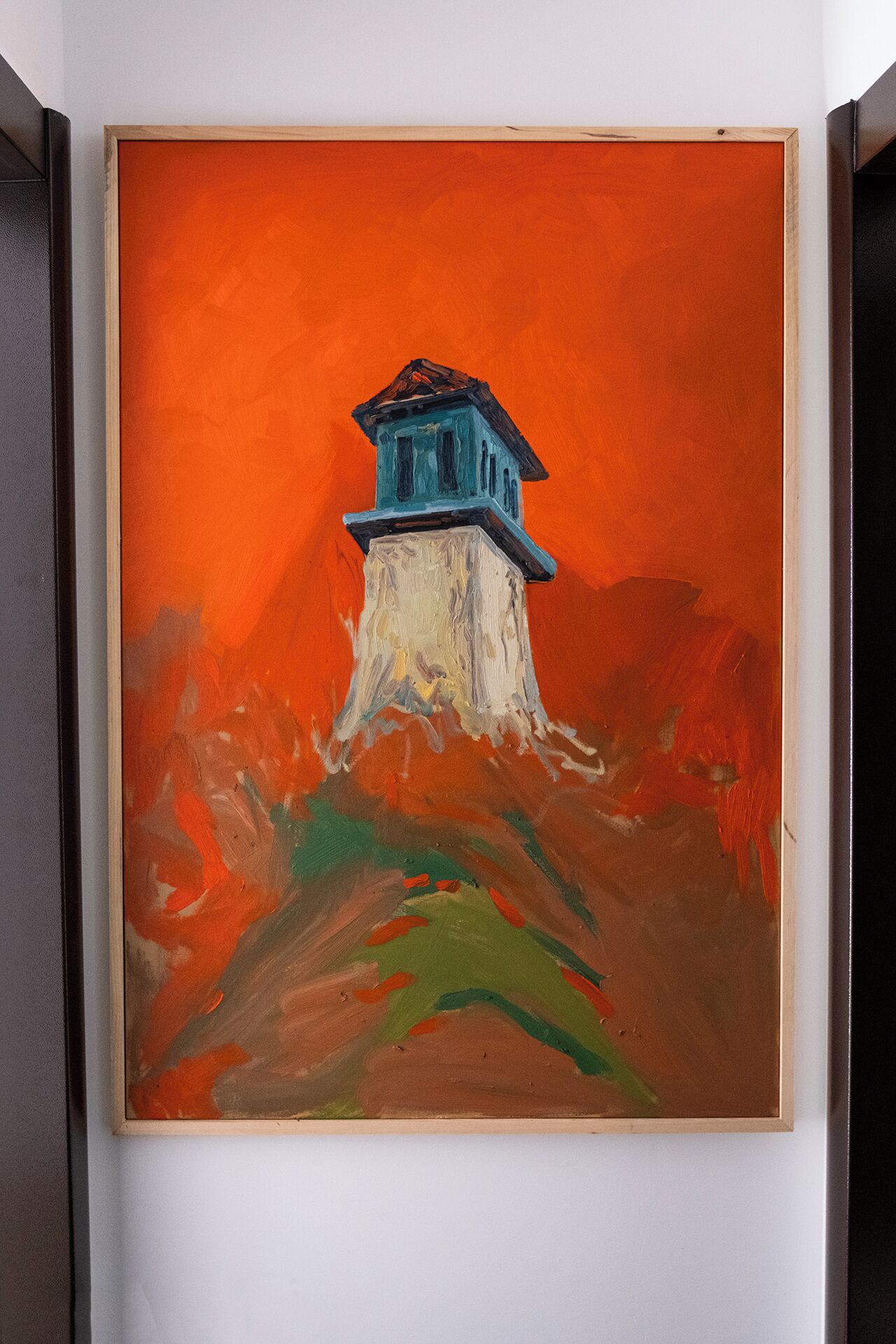Un tableau encadré représentant un phare perché sur une falaise, avec un fond orange.