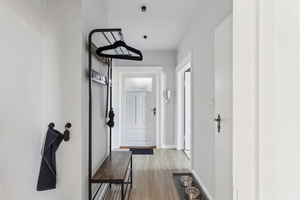 Un couloir avec un porte-manteau, un banc et un espace dédié aux gamelles de chien.