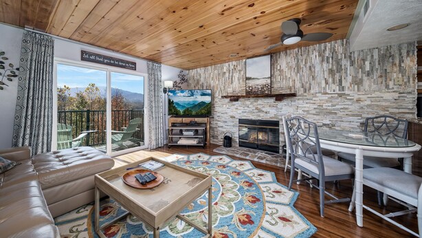 Una sala de estar acogedora con chimenea, techo de madera y un ventanal con vistas panorámicas.