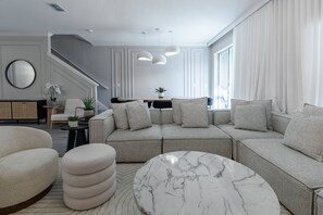 Una sala de estar moderna con un sofá modular, una mesa de centro redonda y una escalera.