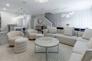 Una sala de estar moderna con sofá, sillones, una mesa de centro y una escalera.
