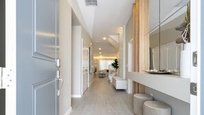 Un corridoio dal design moderno, con pavimento piastrellato chiaro, una panca e una pianta decorativa.