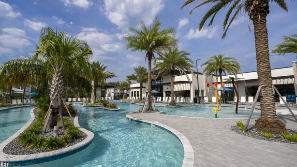 Area piscina con palme, uno scivolo acquatico e un edificio dal design moderno.